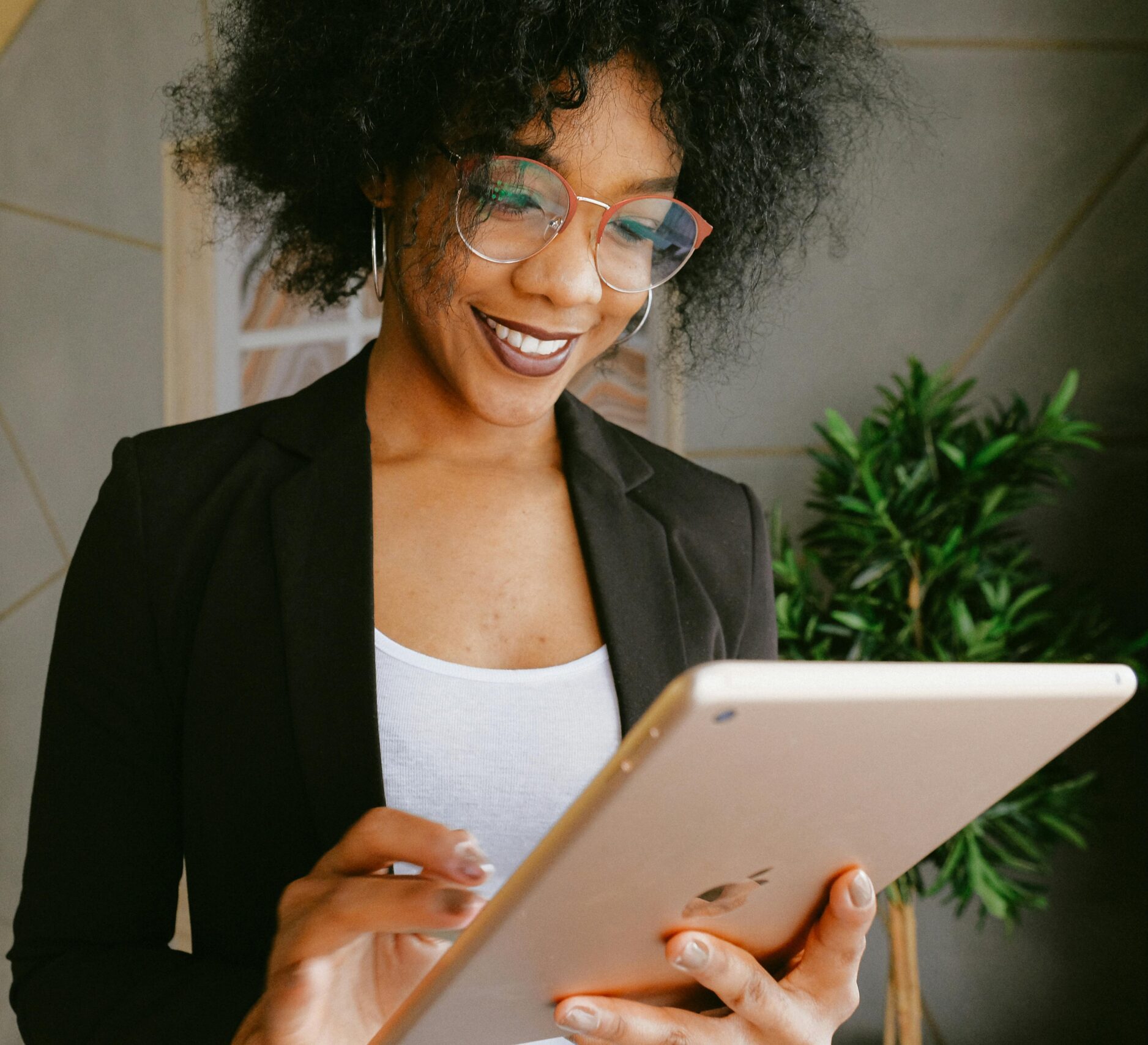 Smiling woman using a tablet in a modern office setting, showcasing technology and business.