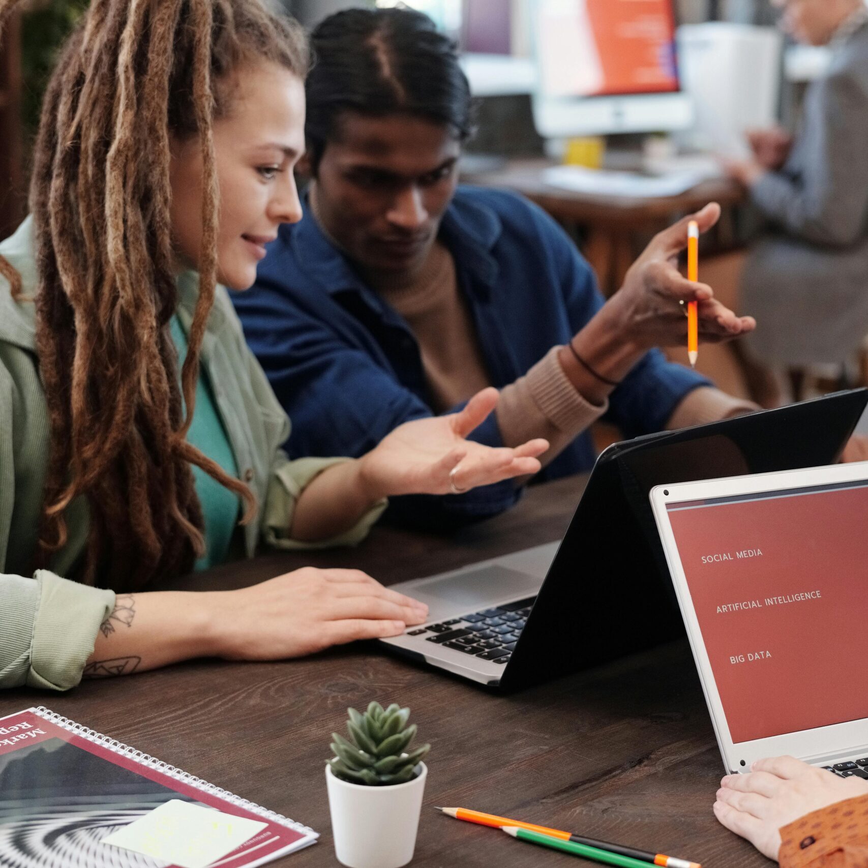 Diverse team collaborating with laptops in a modern office setting, discussing digital evolution.