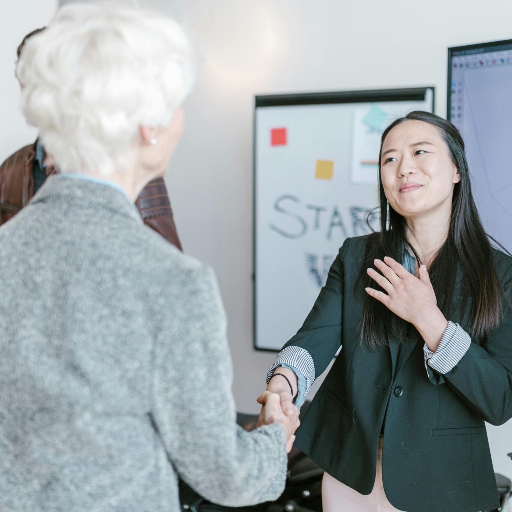 Professional women shaking hands in a corporate office setting, symbolizing a successful business agreement.