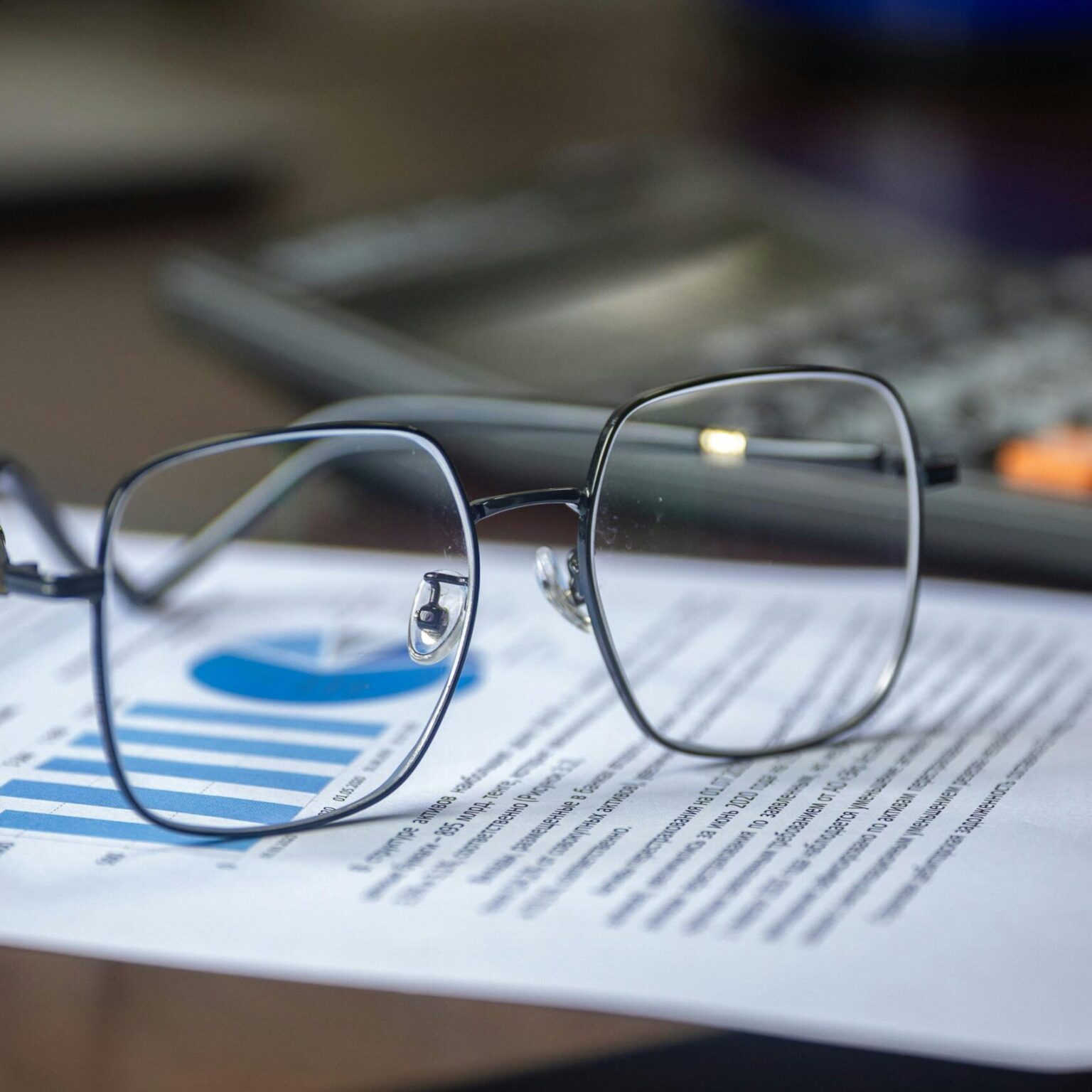 Eyeglasses on financial report with calculator in office setting, highlighting analysis.