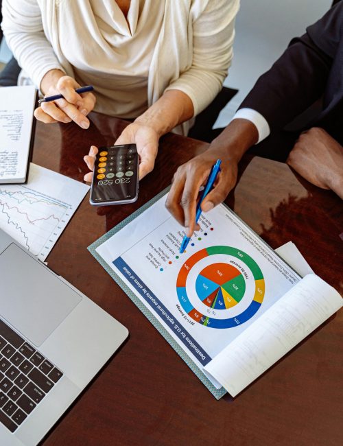 Two business professionals discussing financial documents and strategies at an office desk.
