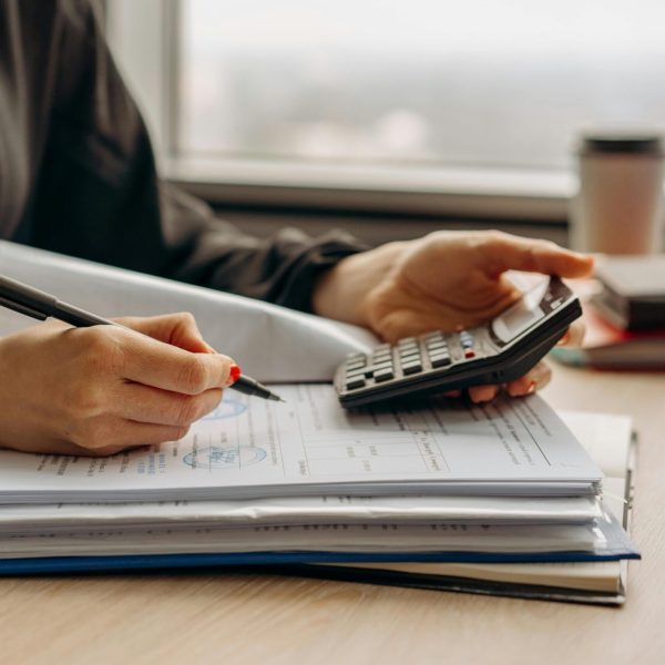 Close-up of person using a calculator with financial documents in an office.